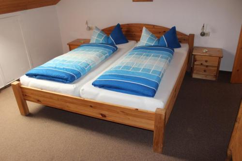 Großes Doppelbett mit zwei einzelnen Matratzen, je einem Kopfkissen und je einer eigenen Bettdecke. An jeder Bettseite steht ein Nachttisch mit einer Nachttischlampe bereit.